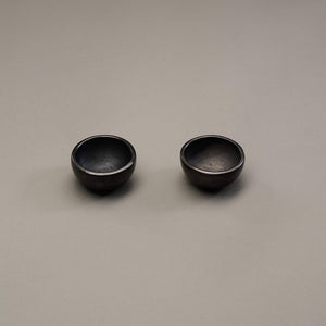 A pair of small black clay mezcal cups.