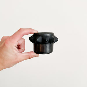 A black clay spiky cup handheld for size persectivel