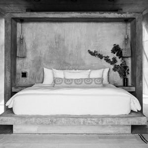 A plush bed featuring a handwoven wool lumbar pillow made in Oaxaca for Javier Studio.