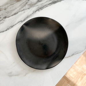 A Oaxacan black clay plate on a marble countertop with hardwood finish in the background.
