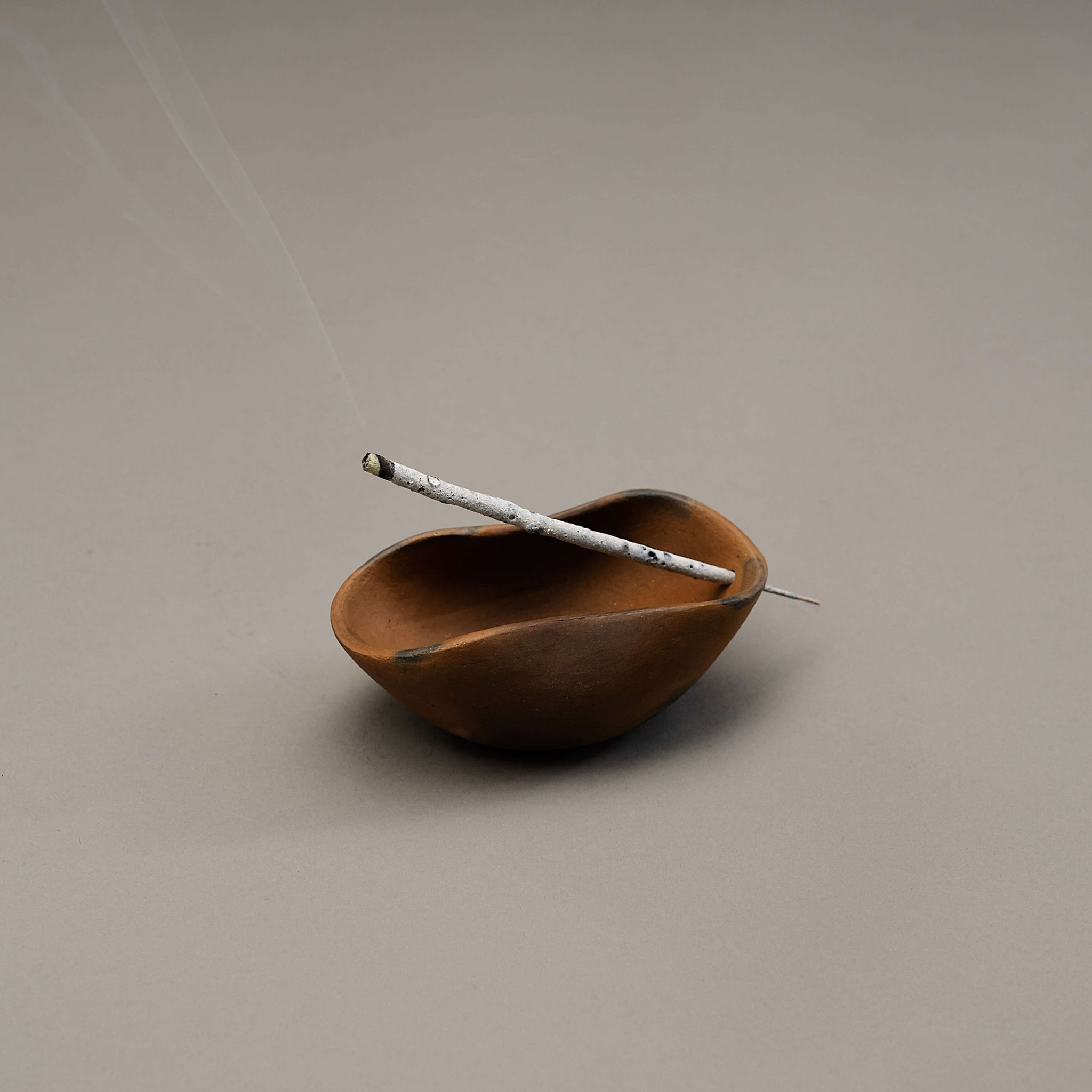 A sculptural incense holder with a copal incense stick.