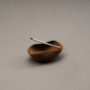A sculptural incense holder with a copal incense stick.