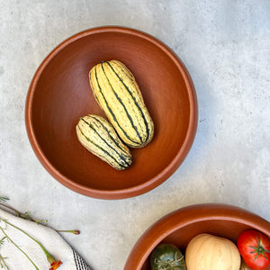 A 10 inch Oaxaca red clay large serving bowl with two squashes.