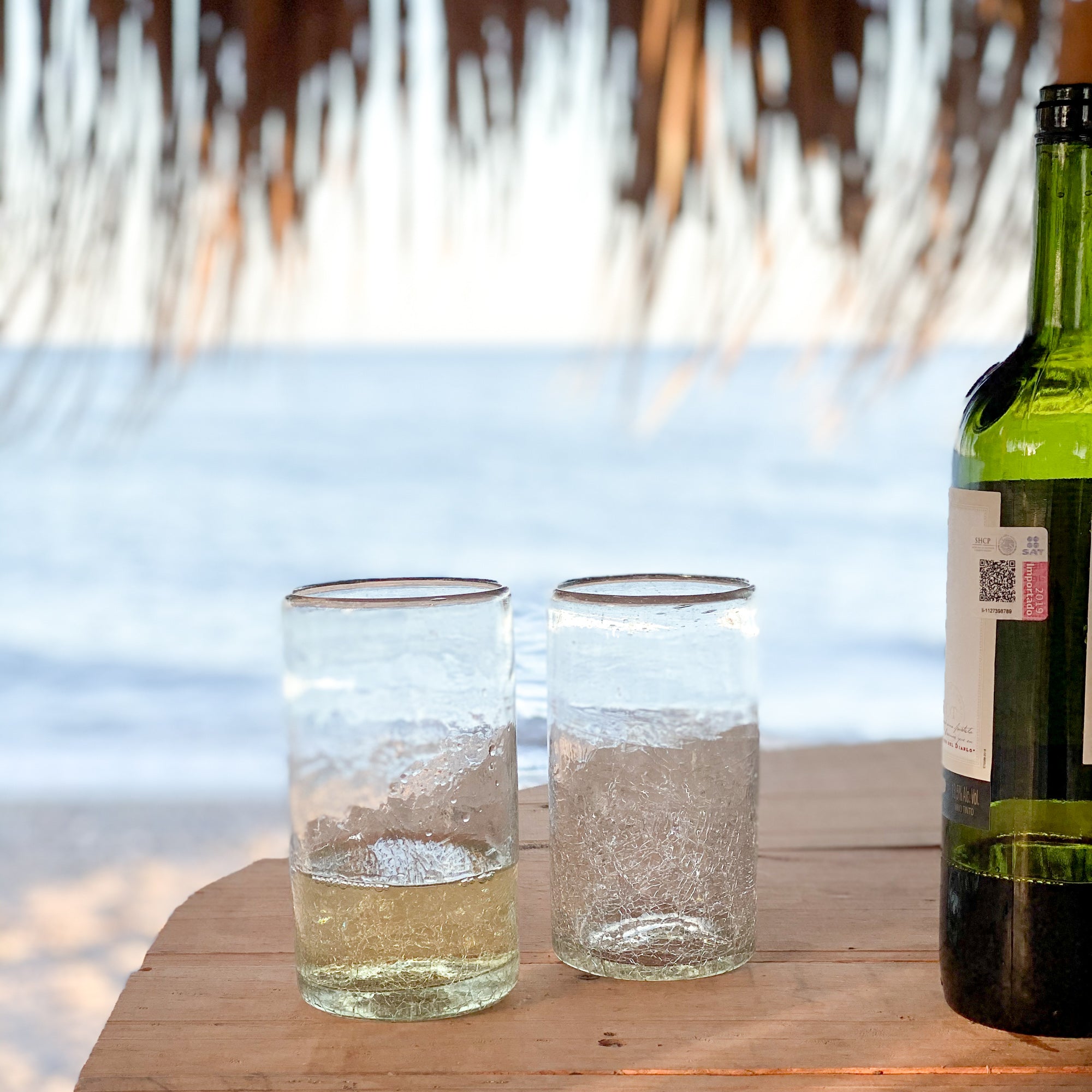 A pair of two Baja glass tumblers on a table overlooking the sea.