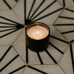 Black ceramic candle on a concrete tile.