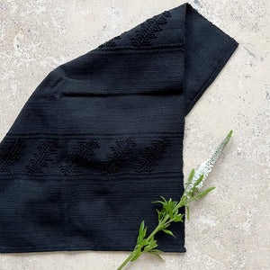 A black cotton napkin made in Oaxaca, Mexico.