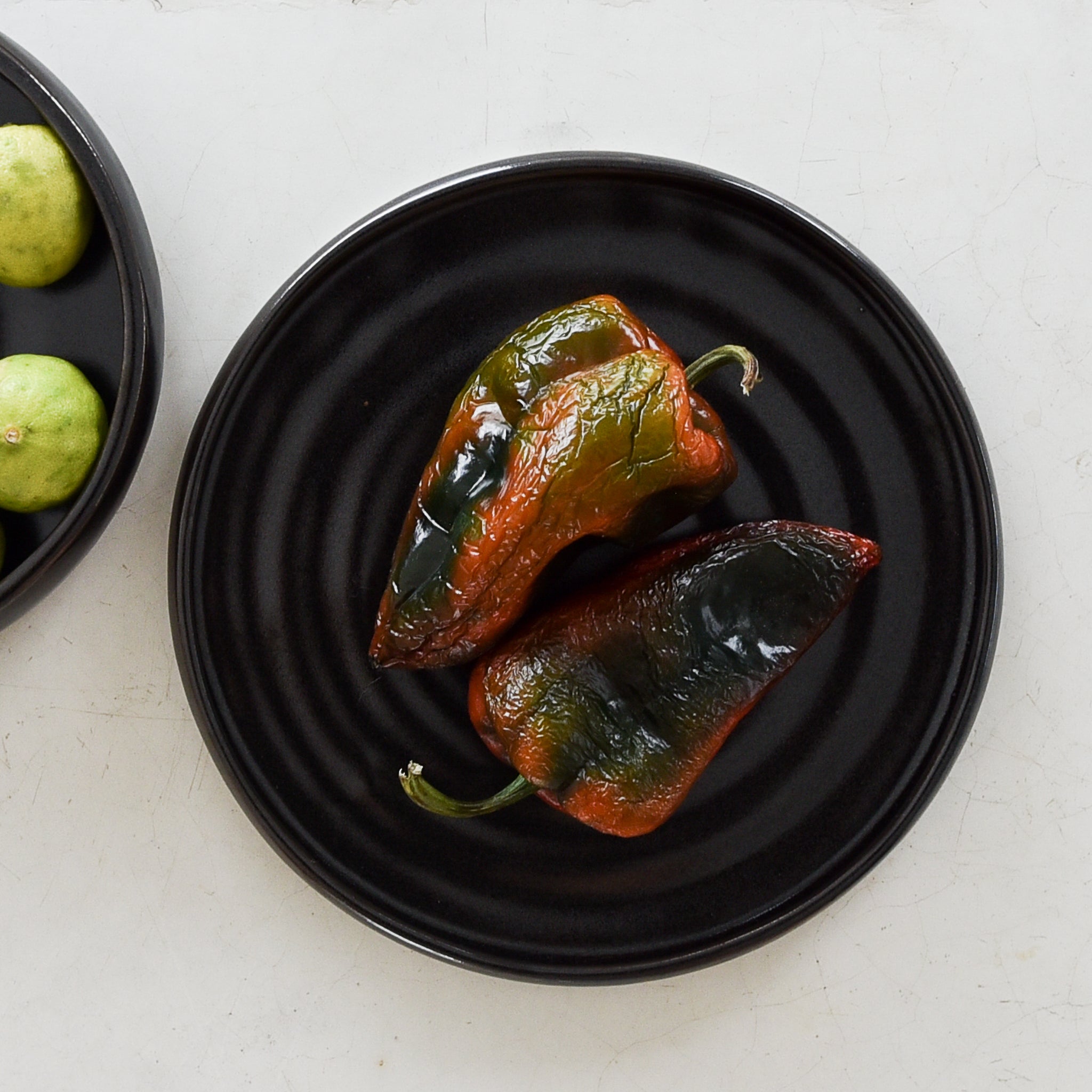 A black stoneware dinner plate with two poblano peppers.