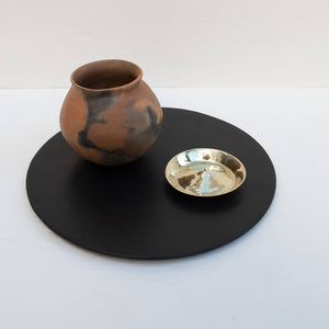 A brass incense holder on a decorative tray alongside a ceramic vase.