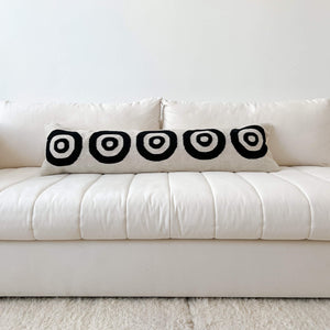 A circulo lumbar pillow in black and ivory on a white couch.