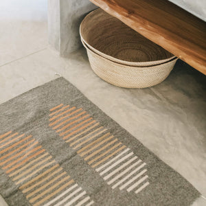 A desierto wool rug in a bathroom next to a pile of large floor baskets.