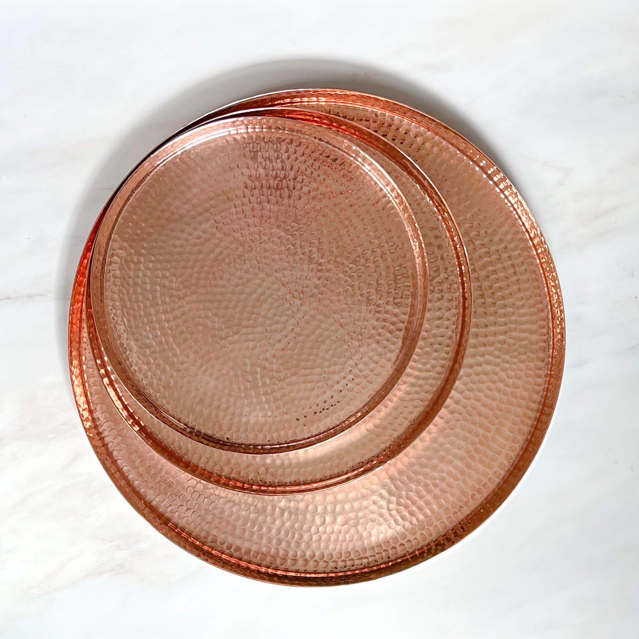 A set of three hammered copper serving trays.