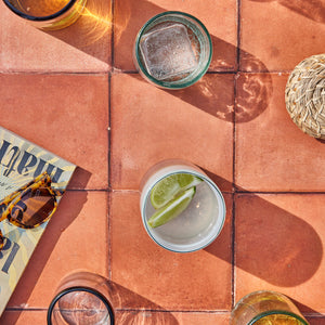 An array of handblown glassware made in Mexico on a terracotta floor.