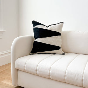 A black and ivory Hidalgo wool throw pillow on an ivory couch.