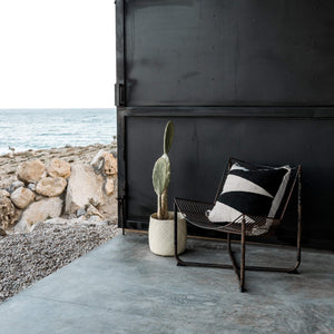 Hidalgo black and ivory wool throw pillow on an outdoor chair next to cactus.