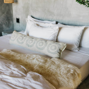 An ivory sheepskin throw in size 2x4 draped over a bed.