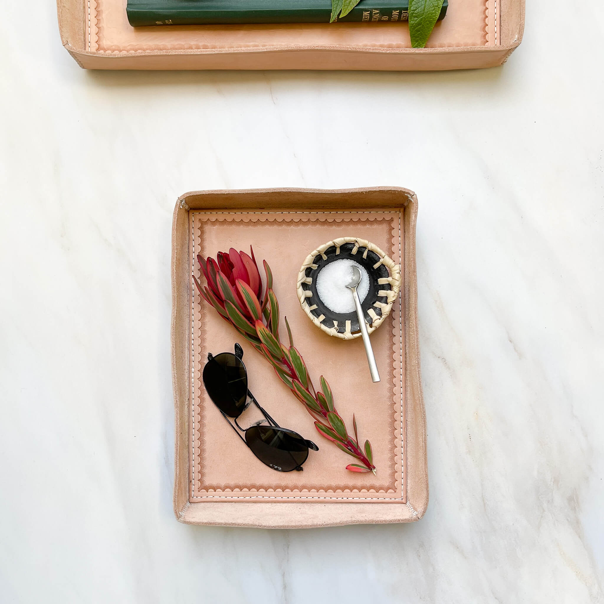 A Javier leather tray in size medium styled with a floral sprig, sunglasses and a salt dish.