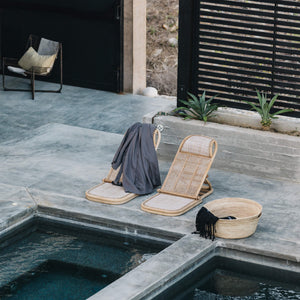 A set of poolside chairs draped by a grey robe made by Cardo Santo, shot by Javier Studio.