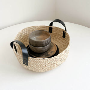 A large Oaxaca basket with black leather handles filled with dishes.