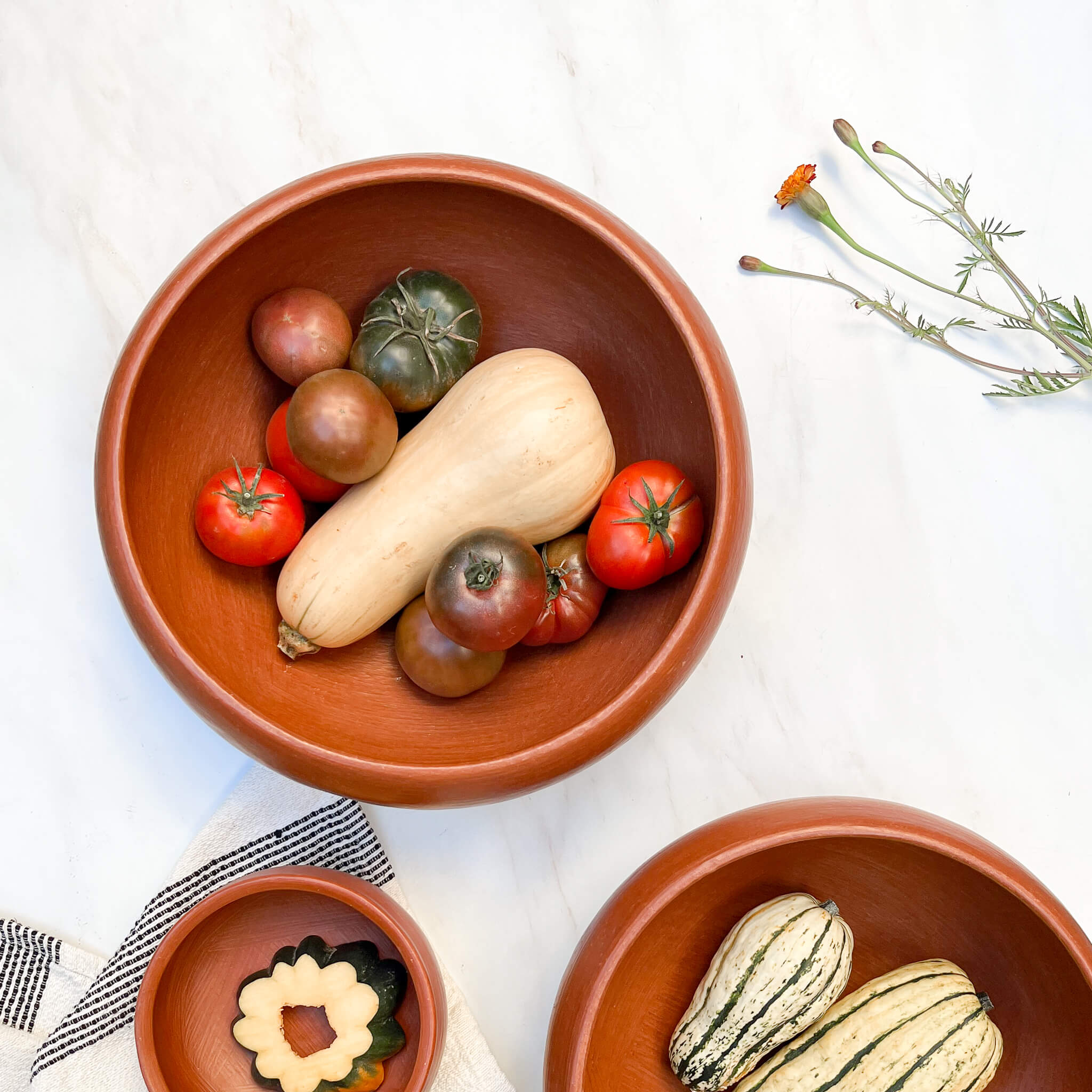 A set of 3 Oaxaca red clay bowls filled with vegetables.