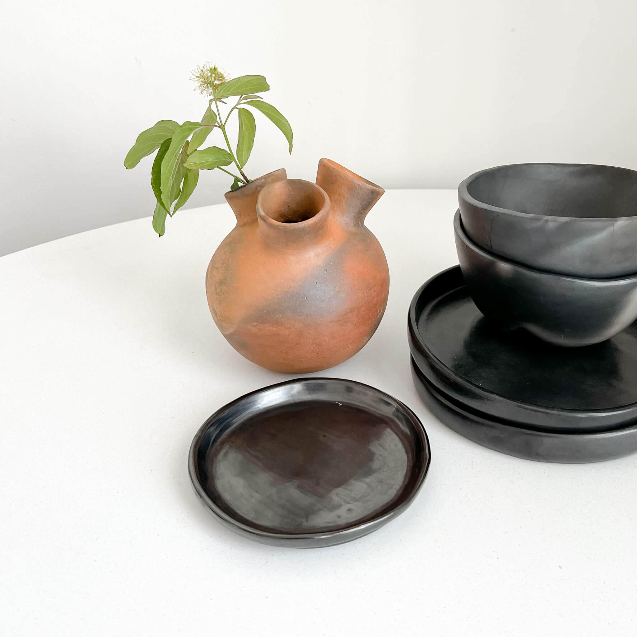 Collection of Mexican pottery including Oaxaca black clay plates and a Pai Pai ceramic vase.