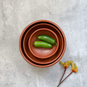 A set of nested red clay serving bowls made in Oaxaca, Mexico.
