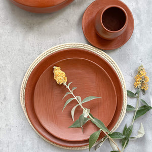 Oaxaca red clay pottery including a salad plate, dinner plate, and stemless mug.