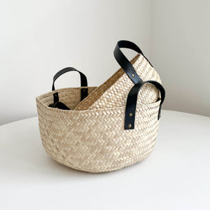 A set of 2 nested Oaxaca storage baskets with black leather handles.