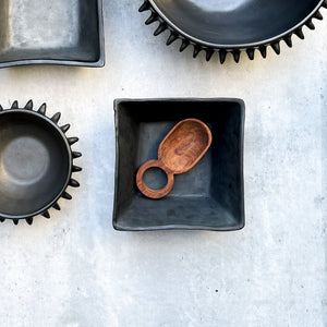 A large wooden Baja spoon in a Oaxaca black clay square bowl.