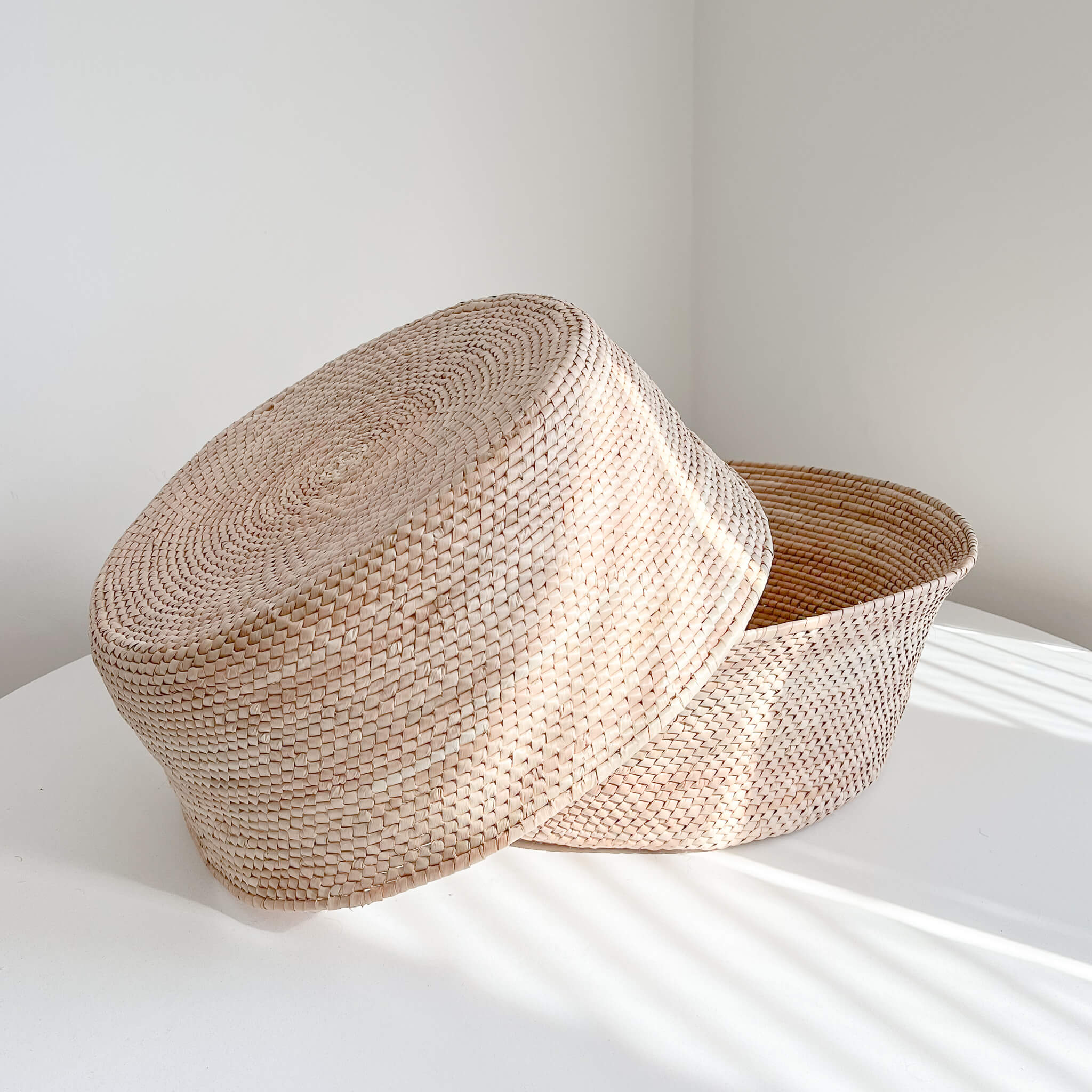 Large handwoven palm floor baskets on a white table.