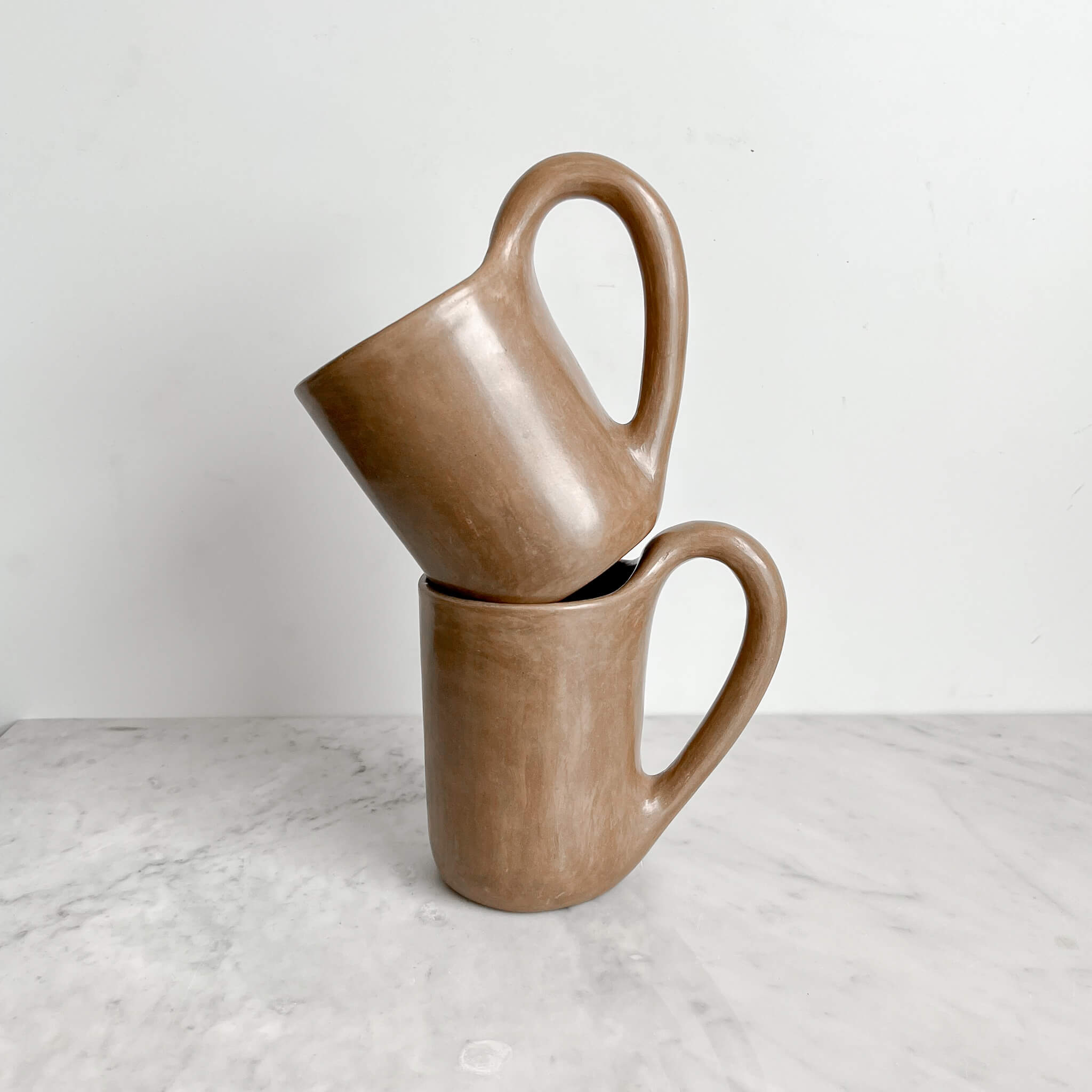 A stacked set of 2 Calapa beige clay mugs made in Mexico.