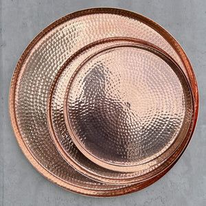 A set of 3 hammered copper trays against a gray background.
