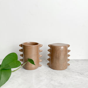 Set of 2 spiky clay mugs on a white marble counter.