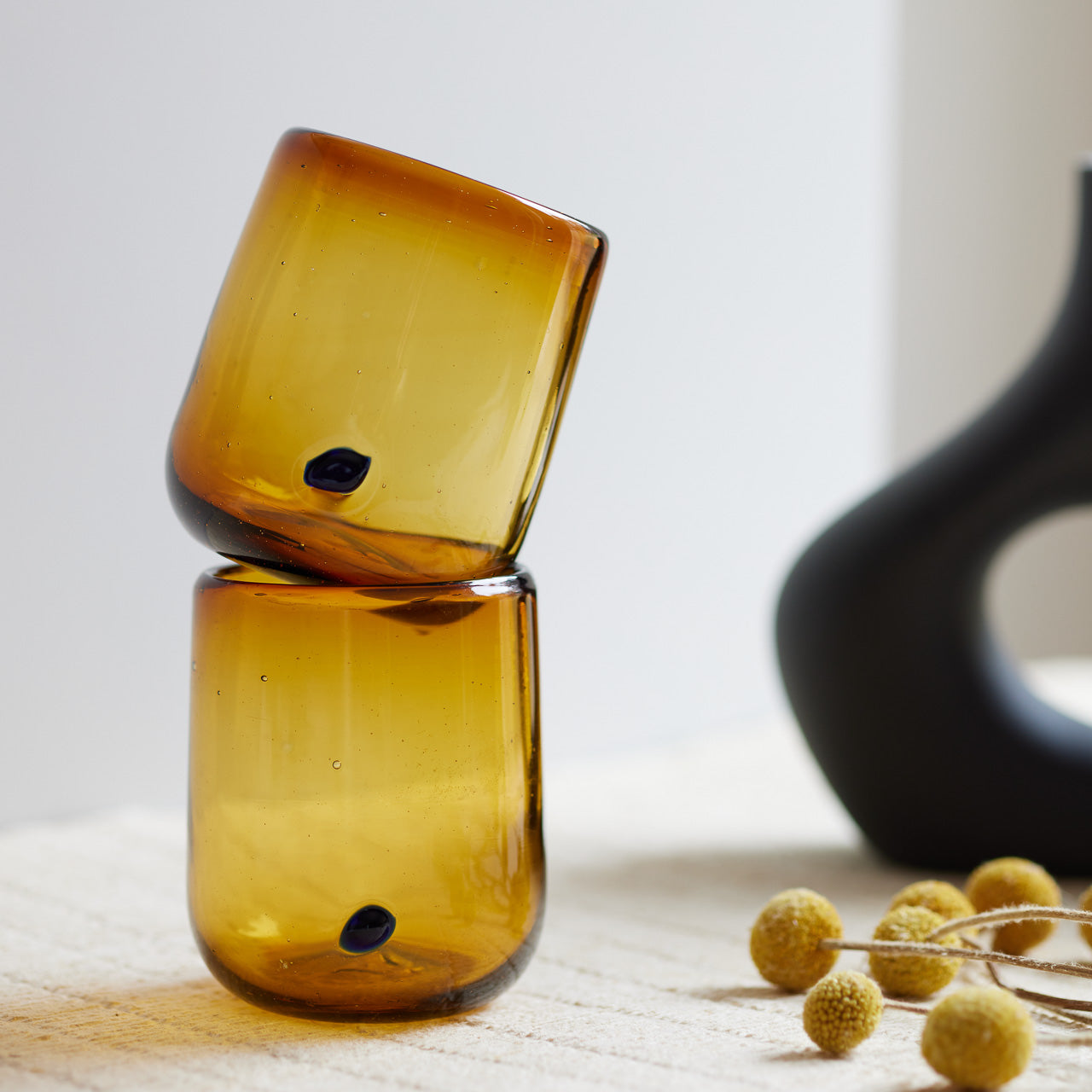 A pair of stacked amber and azul handblown glasses.
