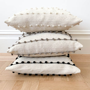 A set of stacked wool throw pillows made in Mexico.