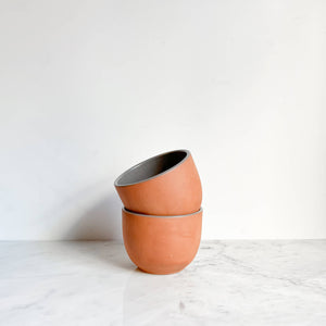 A set of stacked terracotta bowls on a white marble counter.