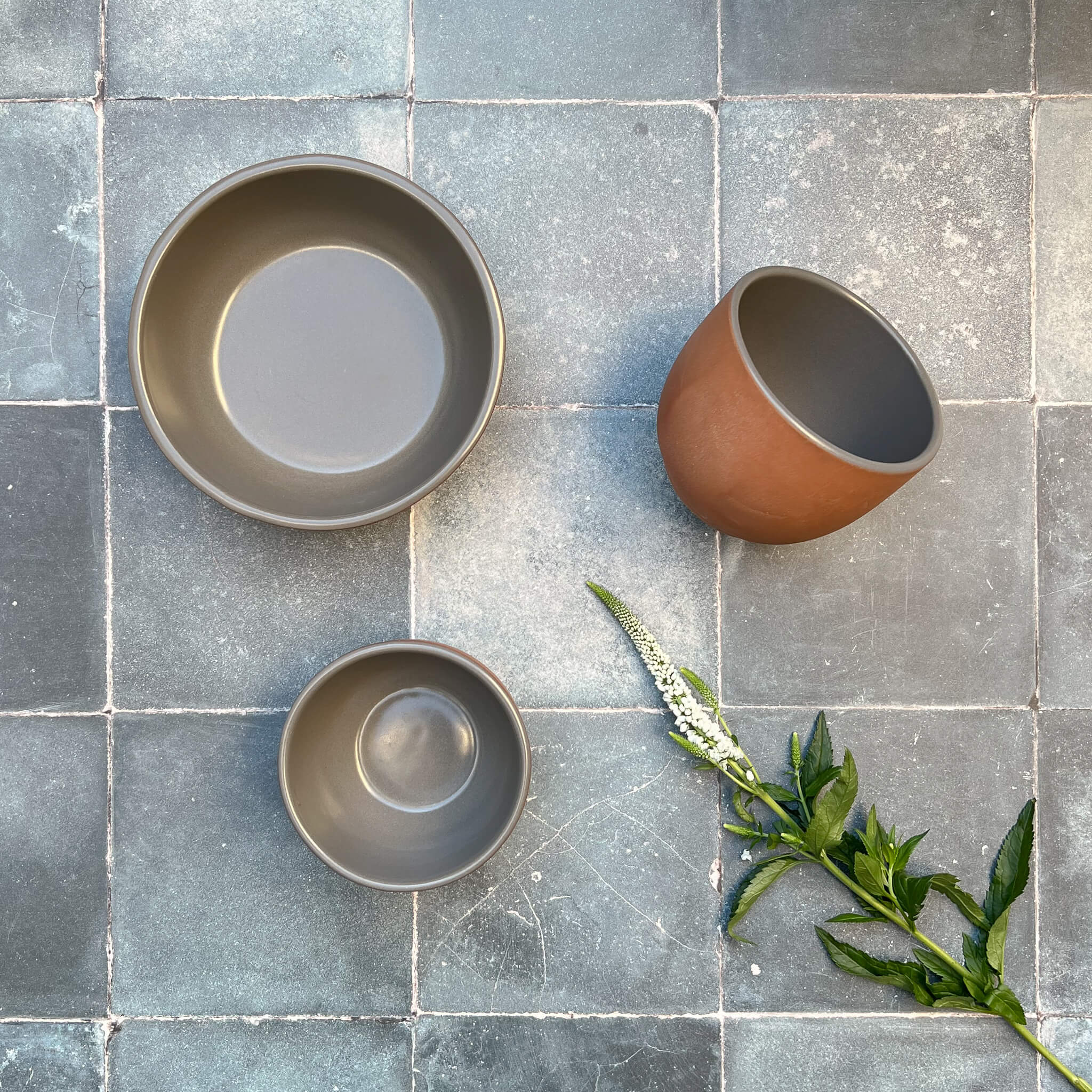 A collection of terracotta bowls with gray glazed interior.