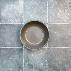 Terracotta gray cereal bowl on tiles.