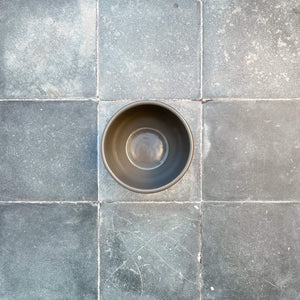 Terracotta deep dessert bowl with gray glazed interior on gray stone tile.