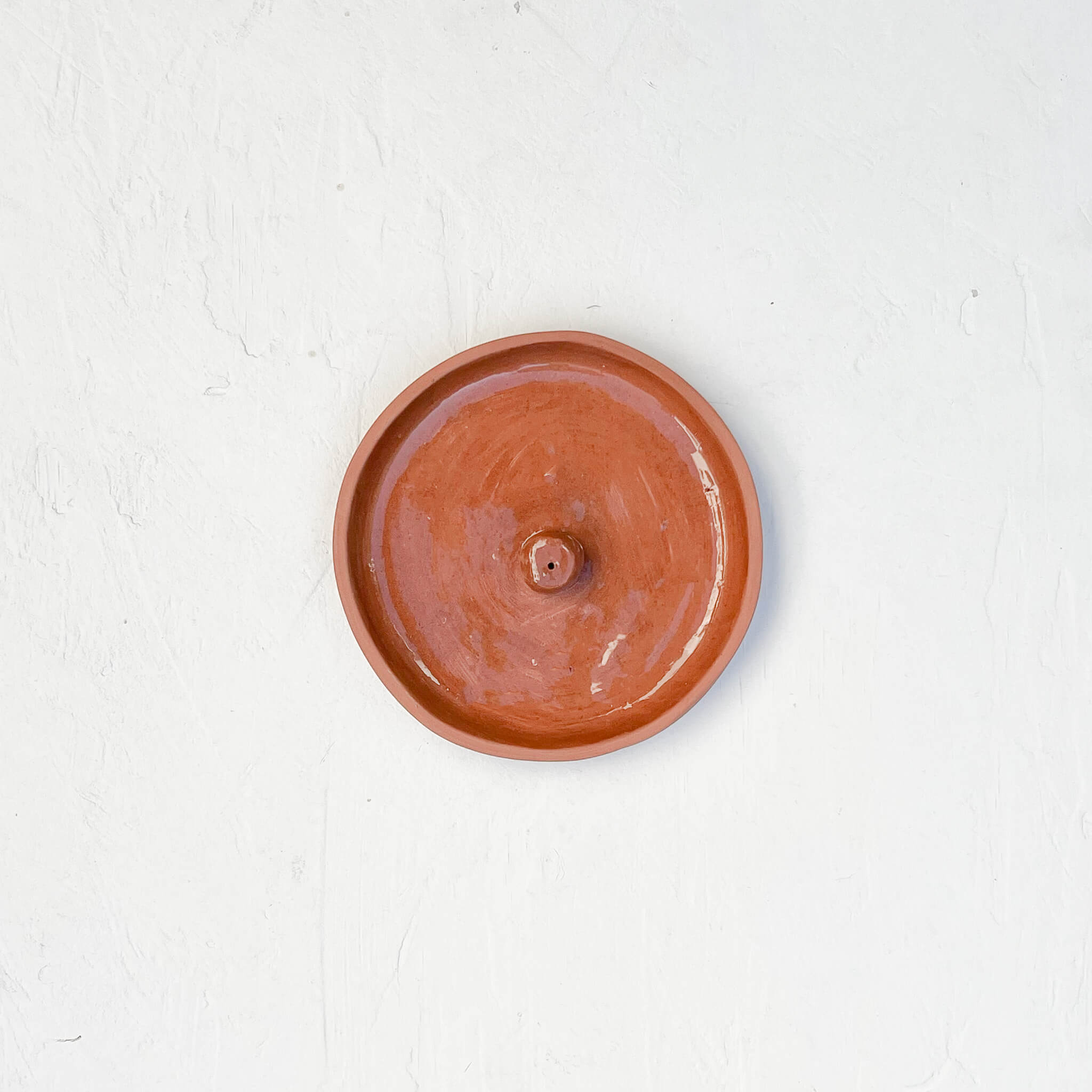 A terracotta incense holder on a white background.