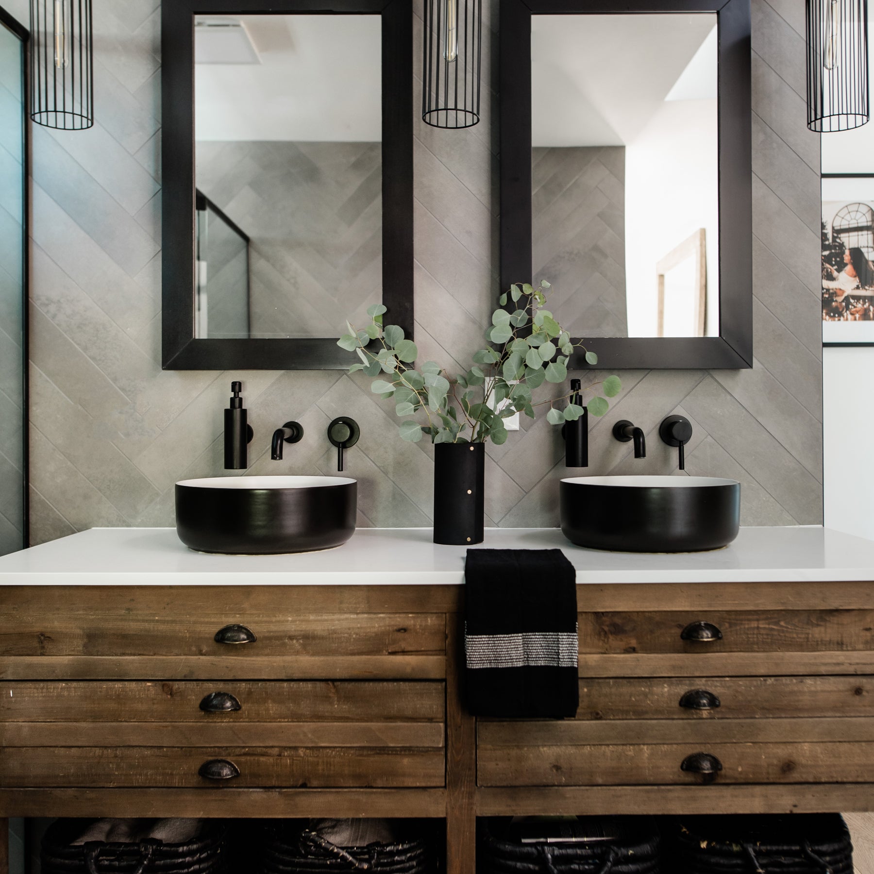 A bathroom vanity with a black leather-wrapped vase, a black cotton hand towel.