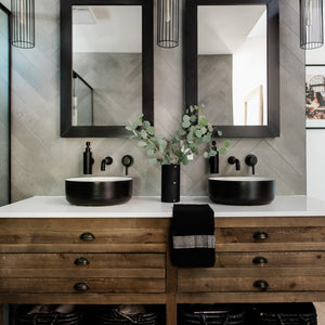A bathroom vanity with a black leather-wrapped vase, a black cotton hand towel.
