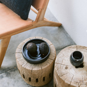 A black stoneware salad plate on a side table.
