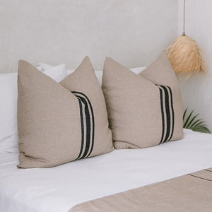 A set of cotton euro shams on a white bed with palm leaf pendant lights.