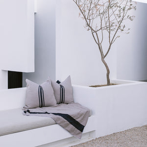 A collection of cotton textiles, including euro sham throw pillows and a cotton blanket on an outdoor couch.