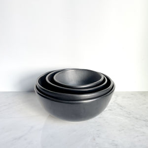 A nested set of four Oaxaca black clay bowls on a marble counter.