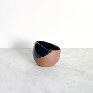 A black dipped terra-cotta ceramic mug on a white marble counter.