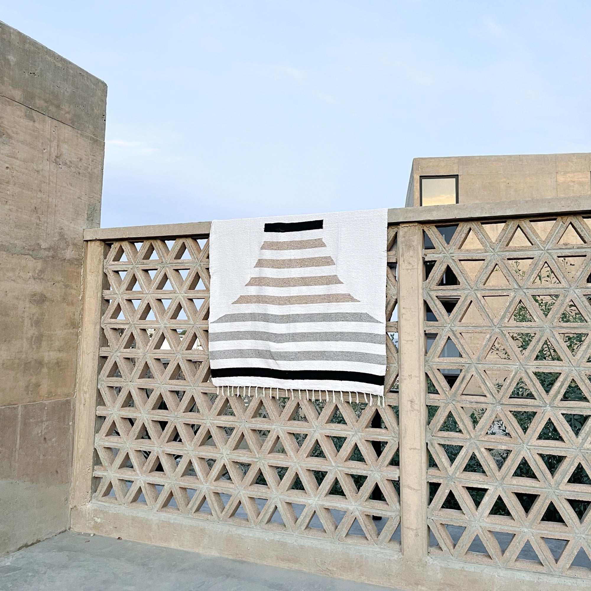 A Mexican beach blanket draped over the edge of a brick geometric fence in Baja.