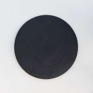 A matte-black round stoneware serving platter.