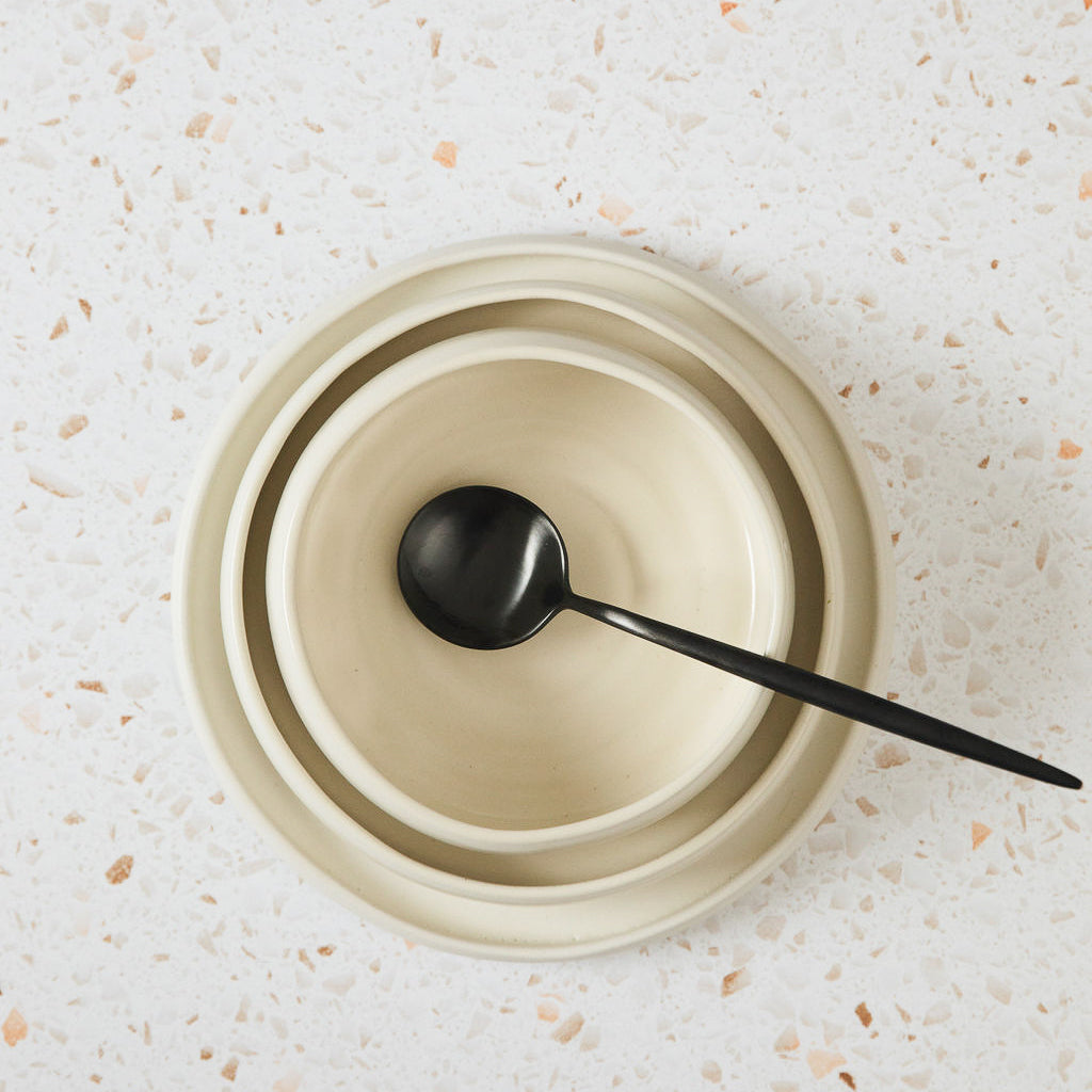 A white stoneware ceramic bowl with spoon.