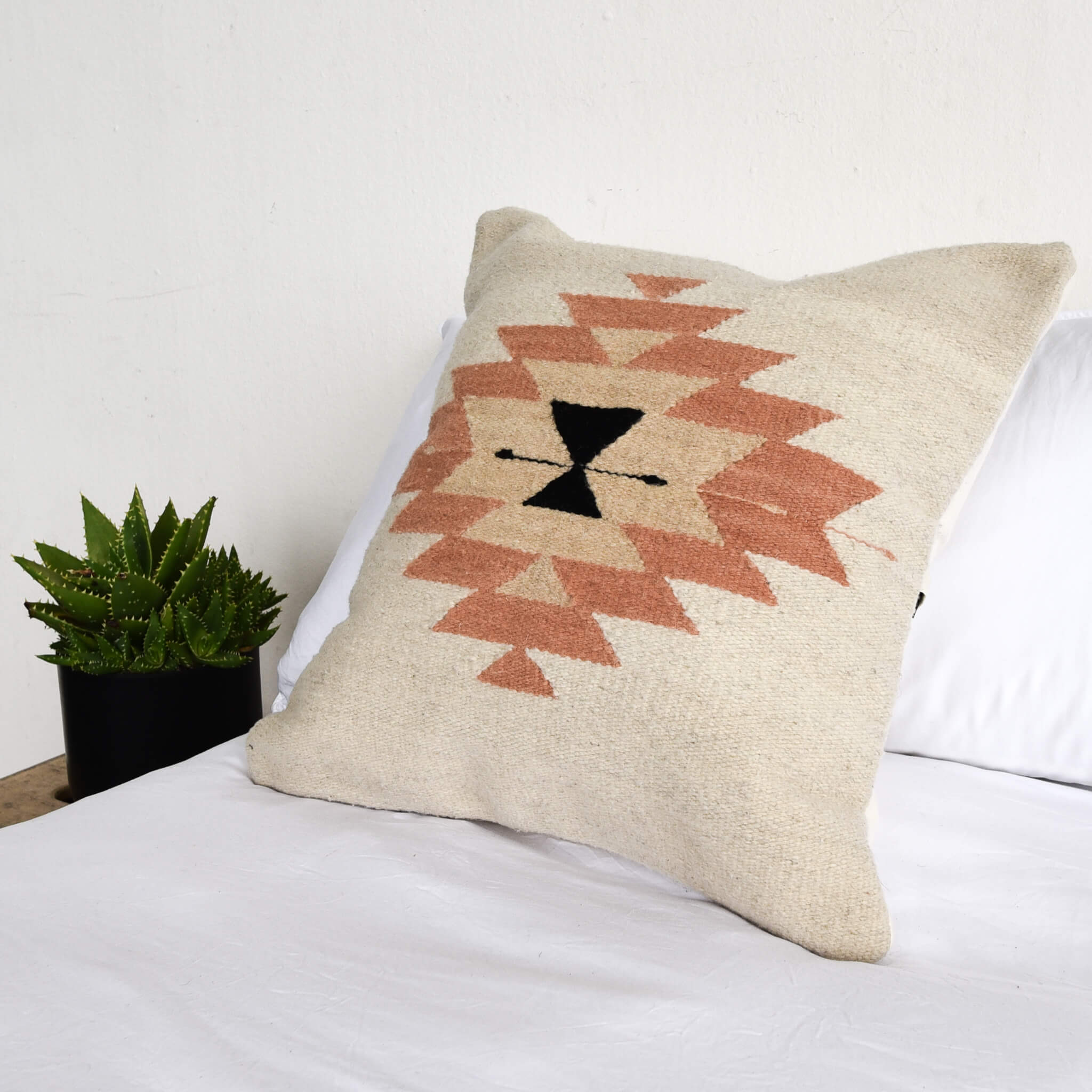 A wool throw pillow made in Oaxaca featuring a Zapotec inspired design.